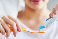 Closeup of woman squeezing toothpaste onto toothbrush