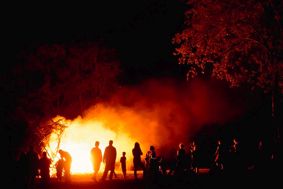 A group of people standing watching a fire in woodland