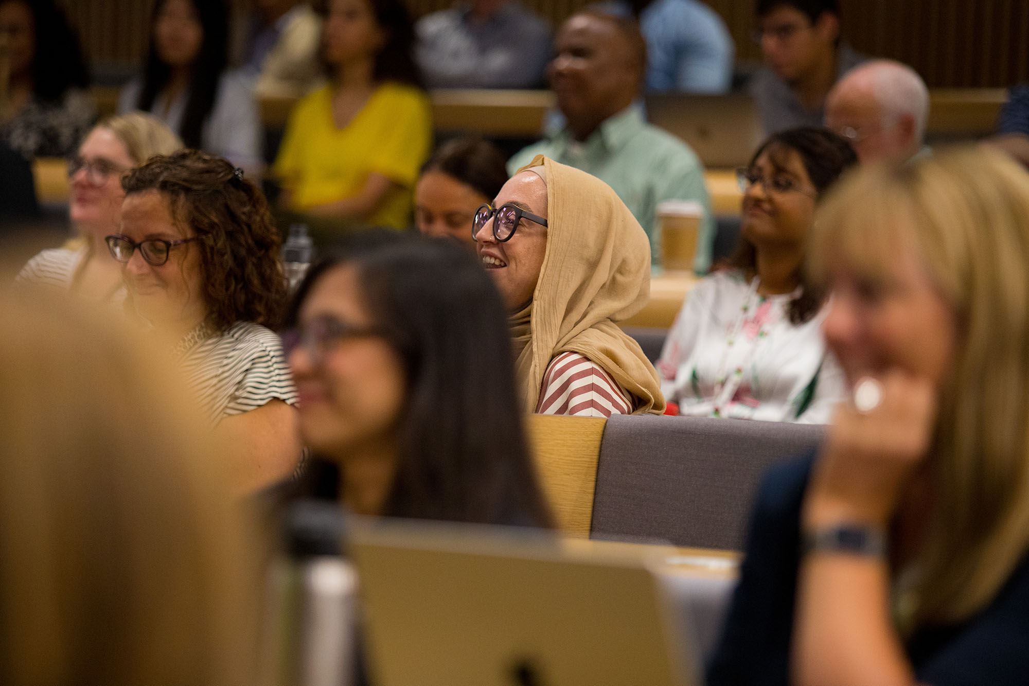 A diverse group of people listening to a speaker in a conference