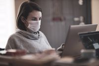 Women wearing a mask working on a laptop