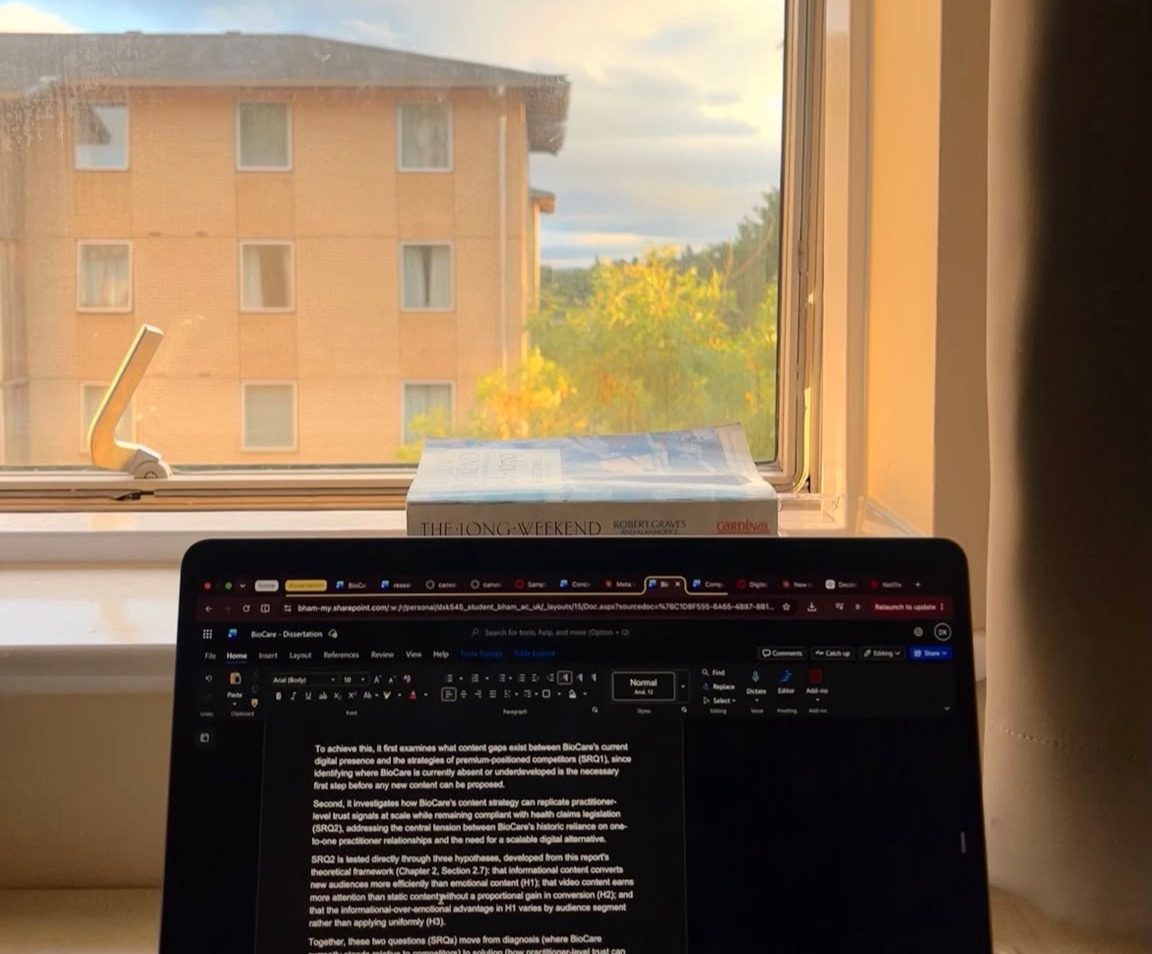 Diya's laptop loaded with a Word document overlooking a beige student accommodation building