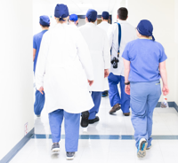 Group of healthcare professionals walking down a corridor with their backs turned to the camera