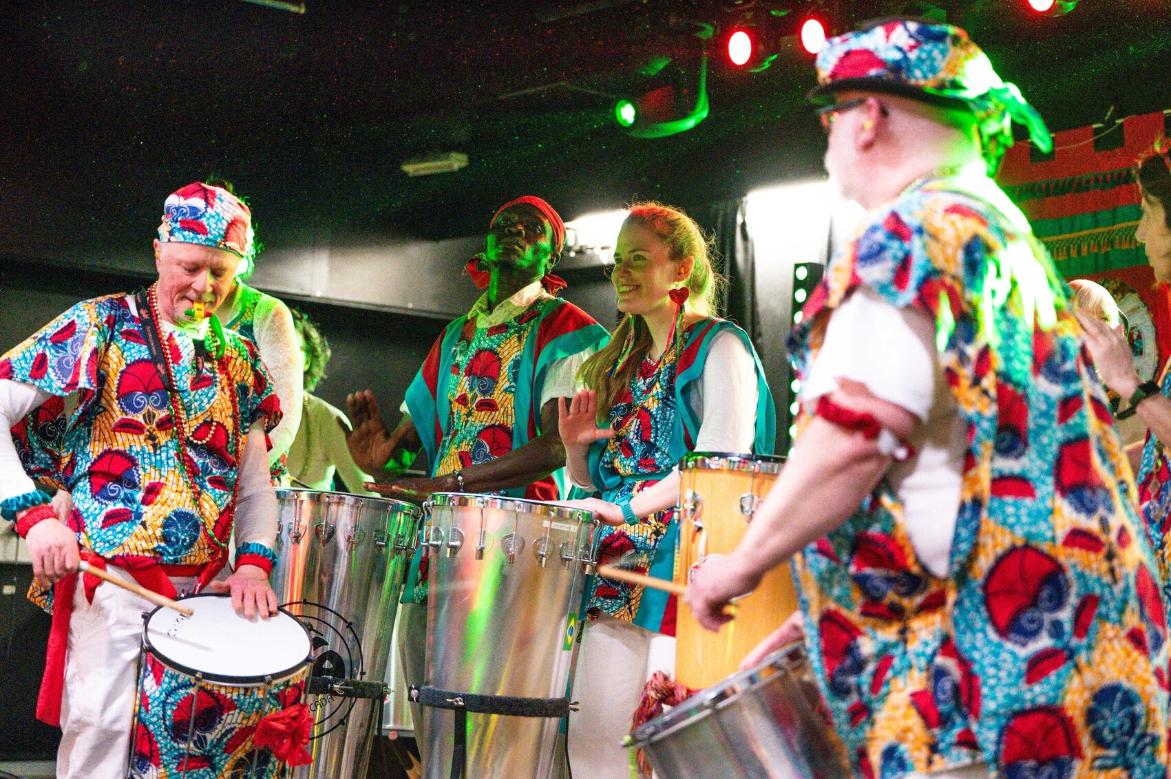 A group of people wearing colourful carnival clothing playing drums