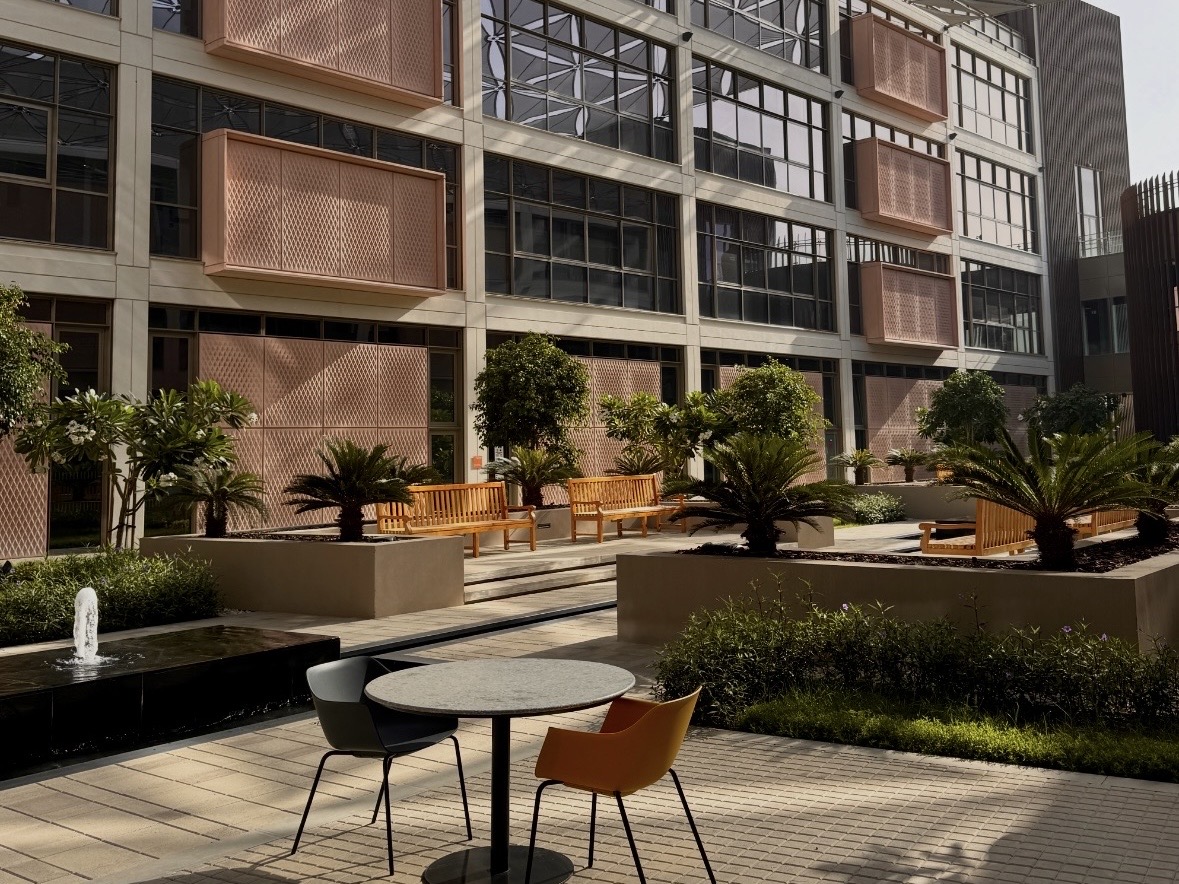 Shaded courtyard at the University of Birmingham Dubai with tables and chairs set next to a water fountain.