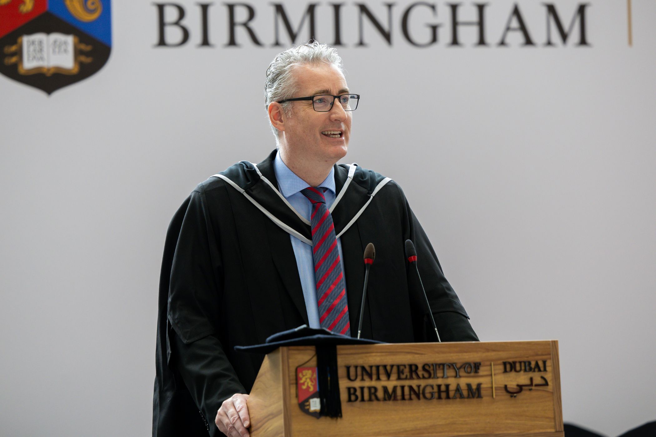 Ben Bailey stood smiling behind podium at graduation.