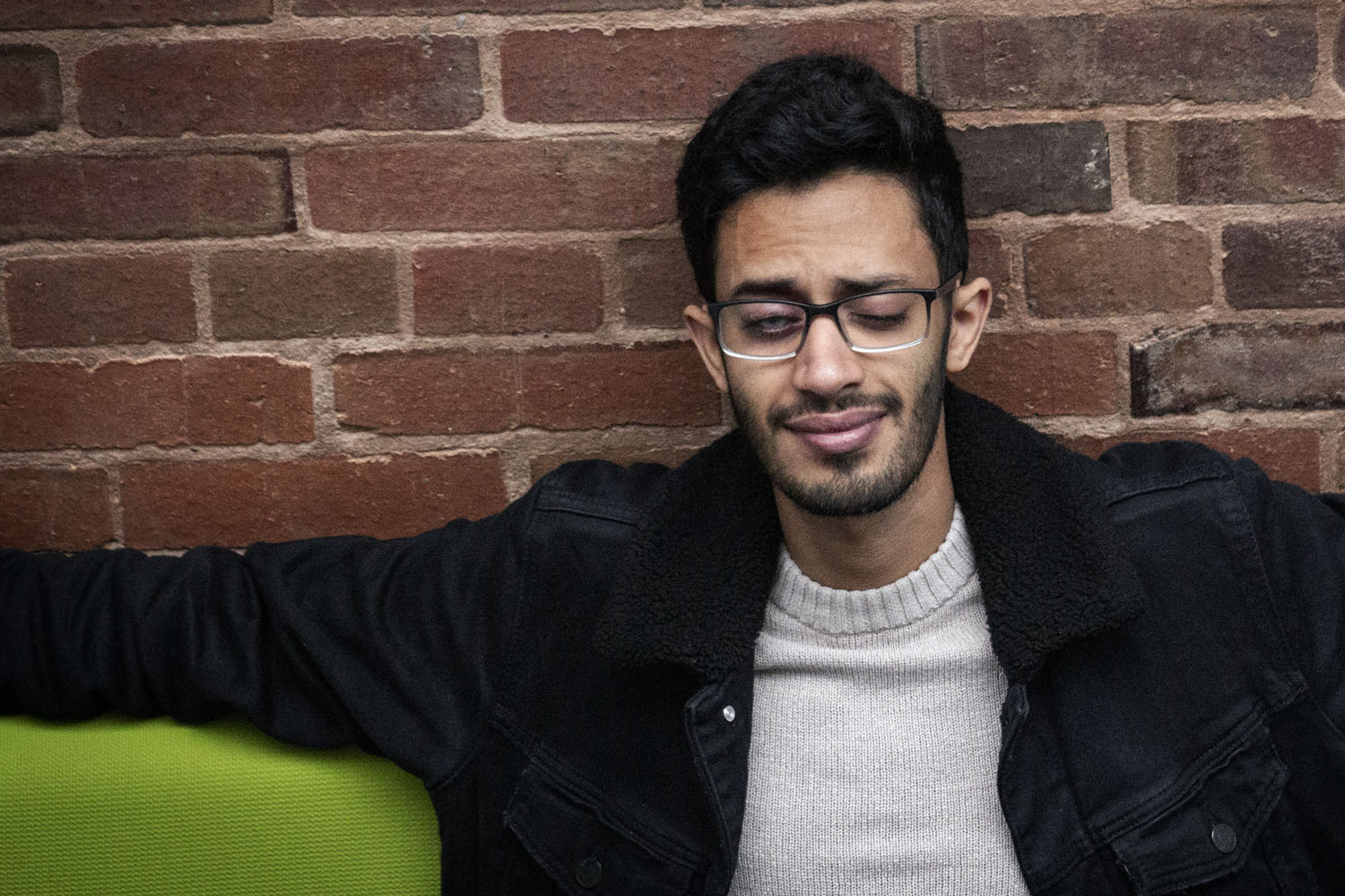 A man sits in front of a brick wall