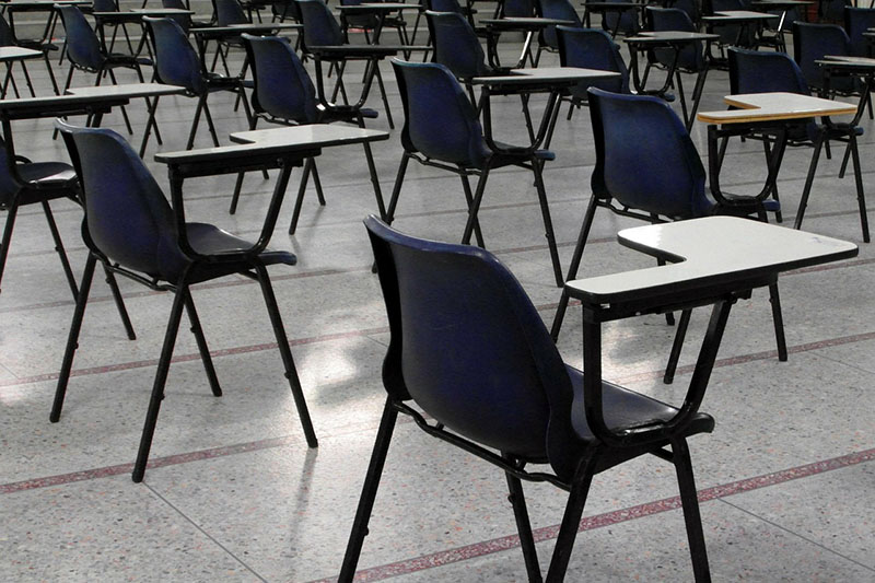 Rows of empty seats in a room set out for examinations