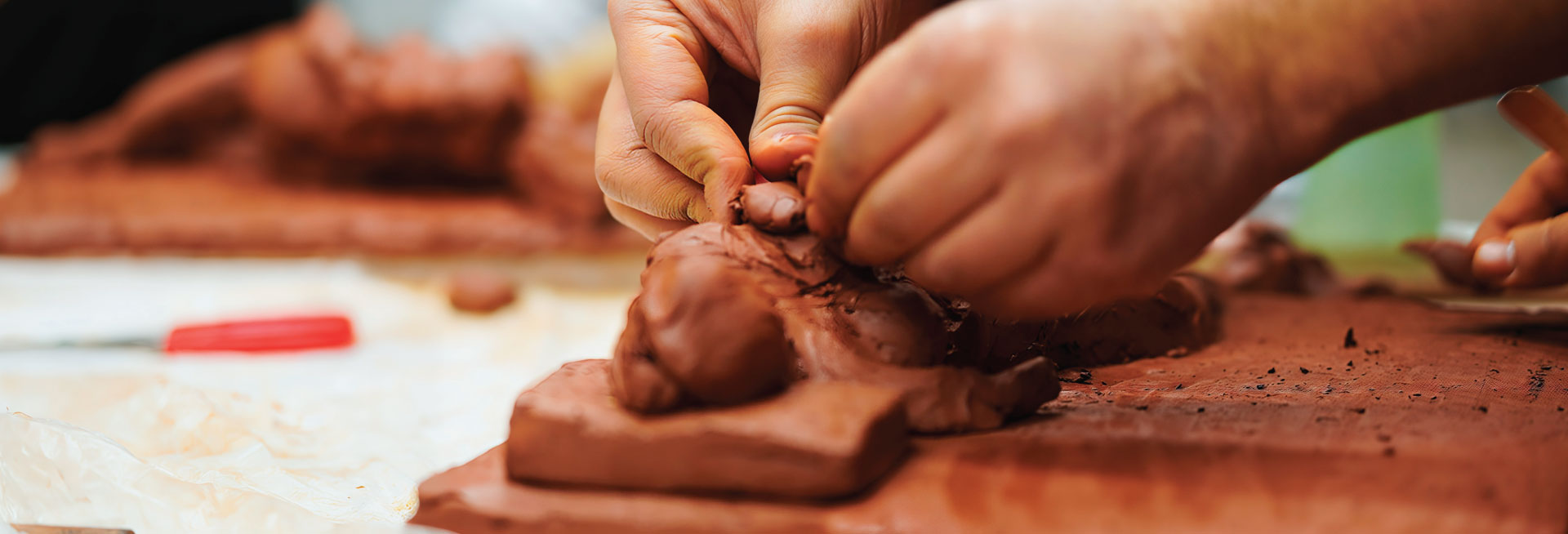 A pair of hands work with clay to make a 3D tile.
