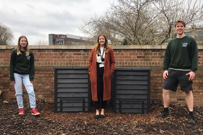 Team stood on campus next to a compost container