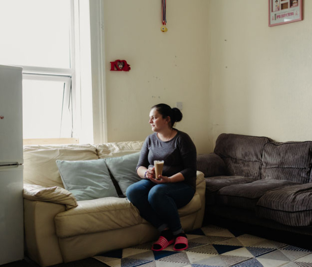 A woman sits on a sofa with a drink
