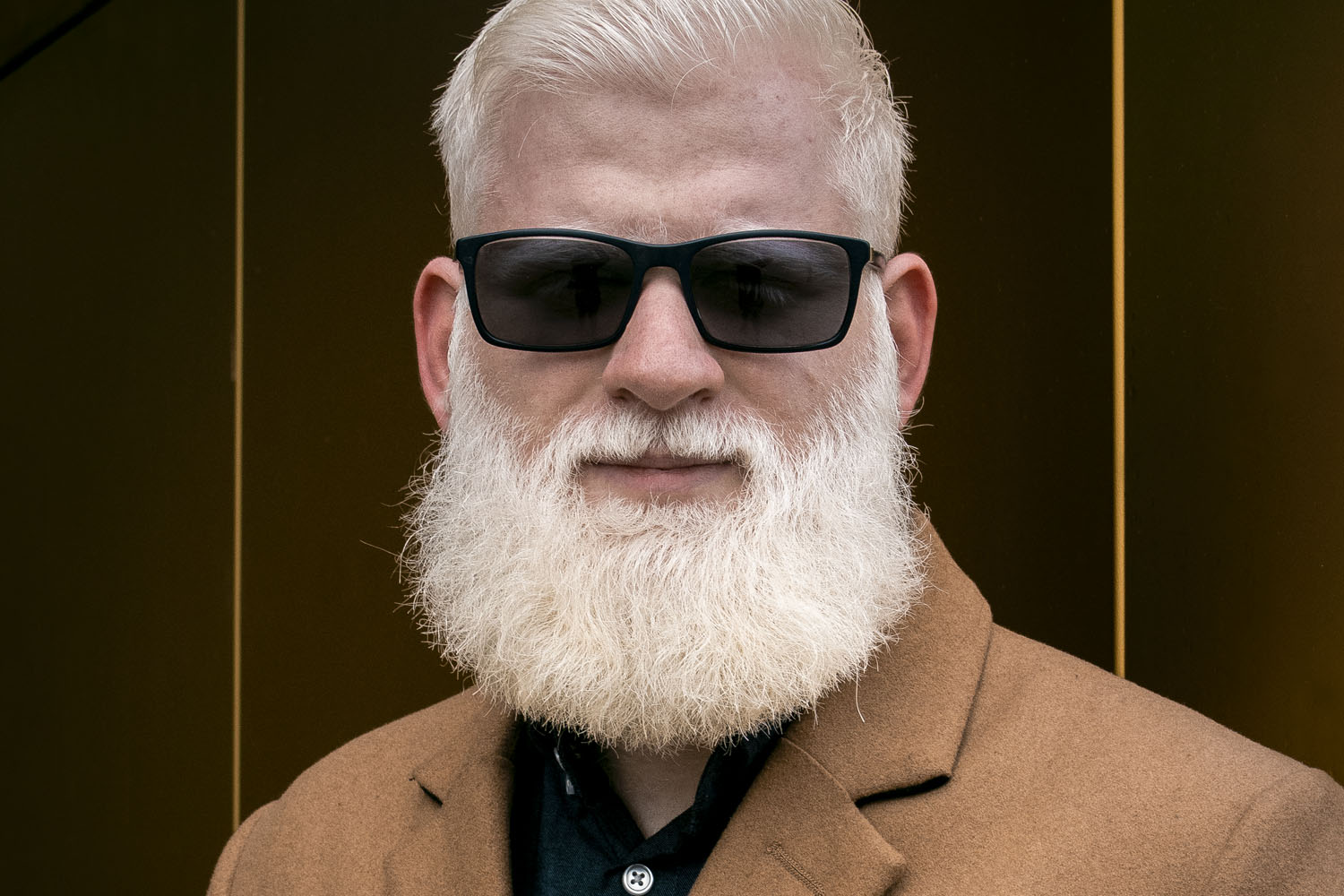 A man in dark glasses looks at the camera