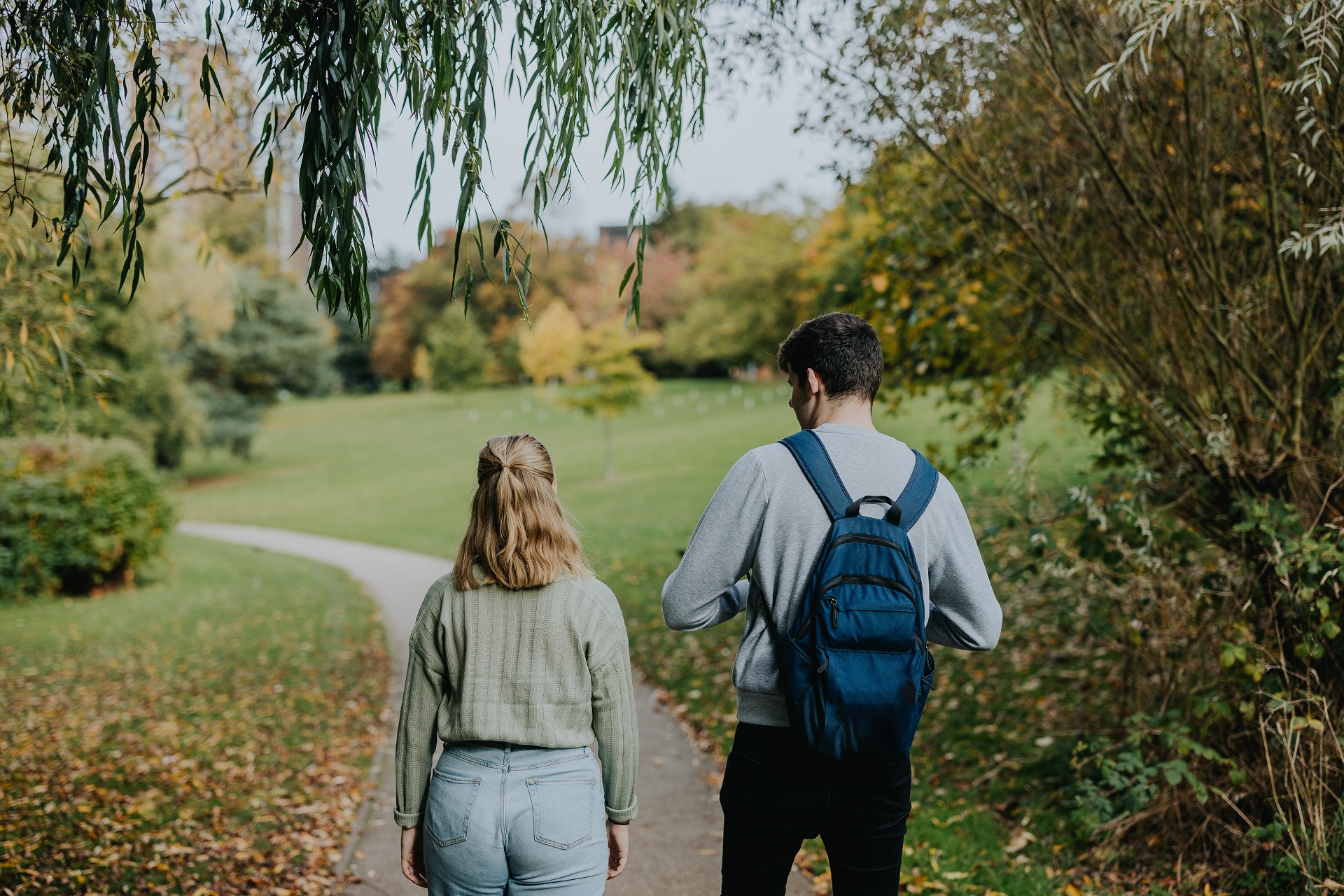 Female and male student walking down a path through a park