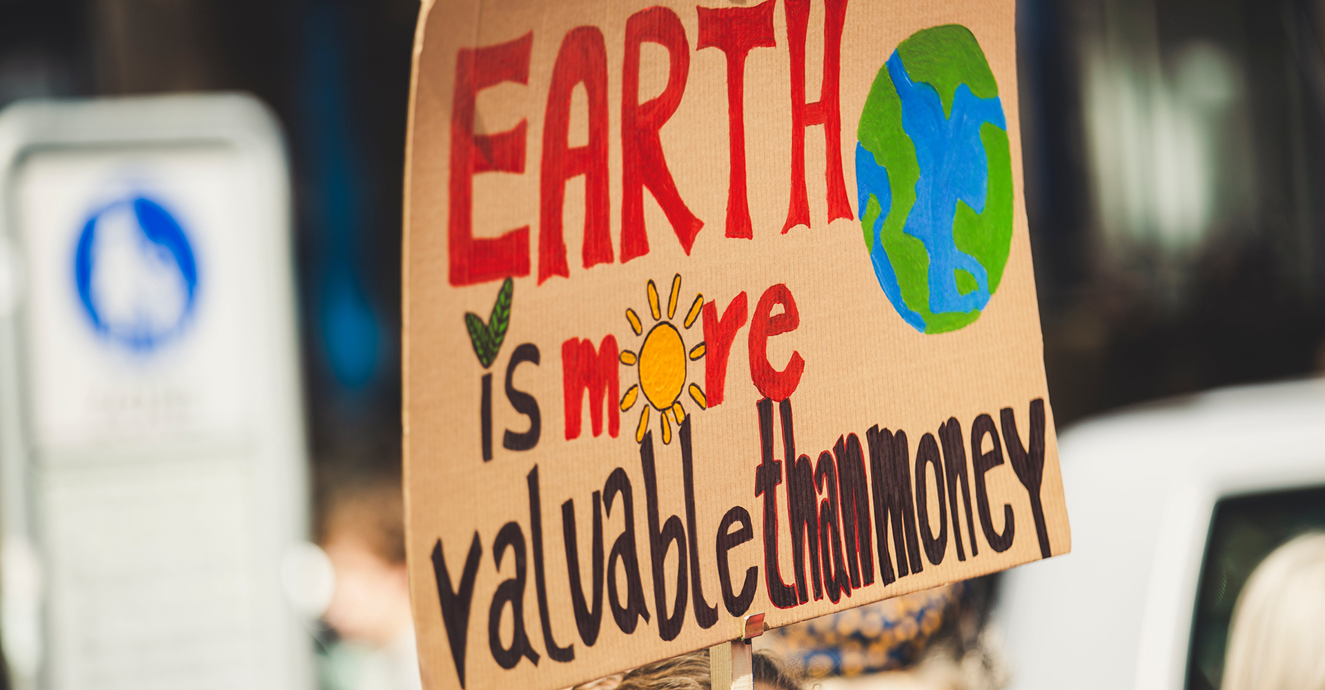 A protest sign stating 'Earth is more valuable than money'