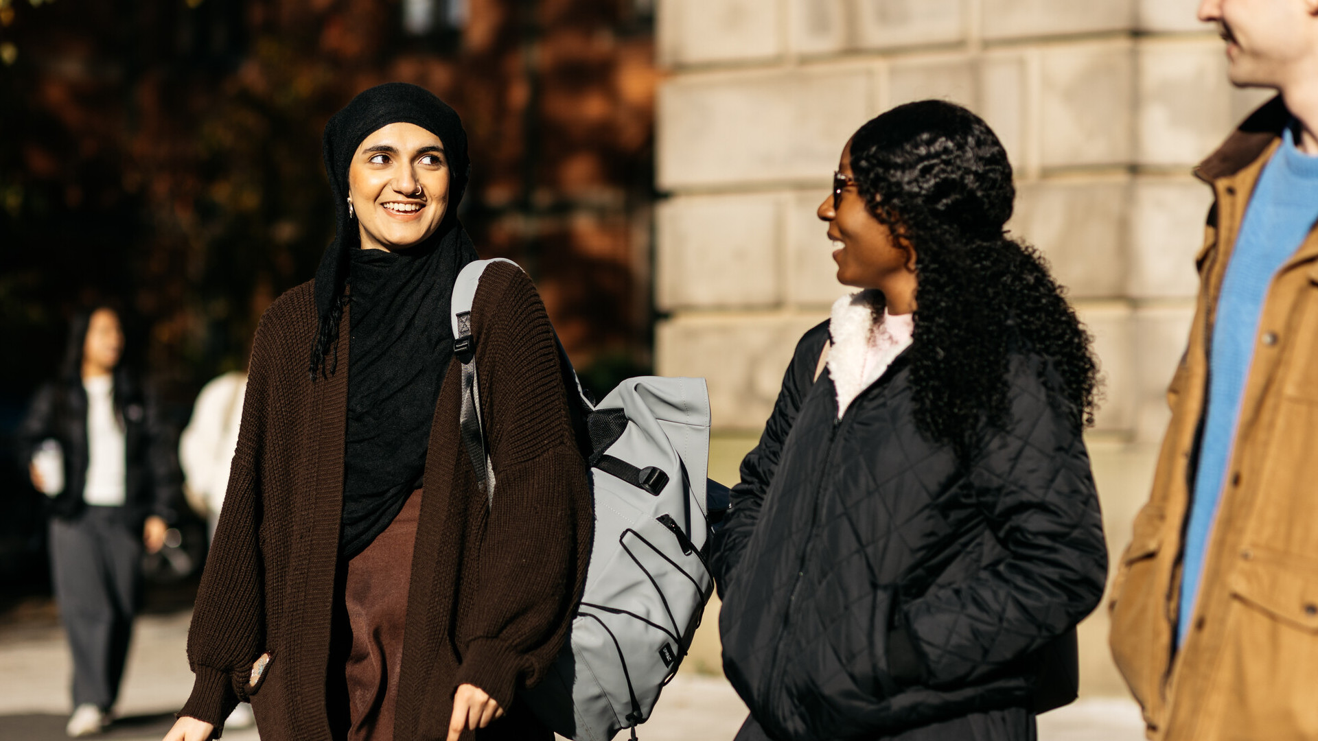 Three students walking on campus smiling