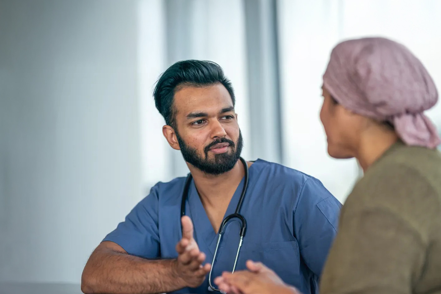 A male doctor in consultation with a female patient wearing a head covering
