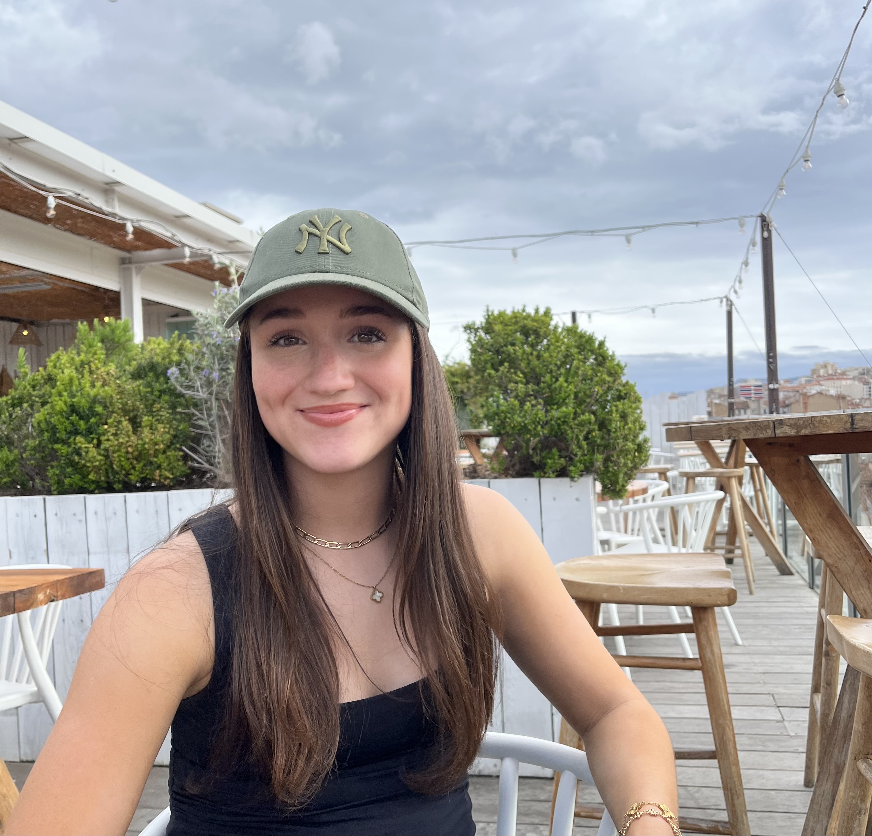 Woman sat outside at a restaurant, smiling.