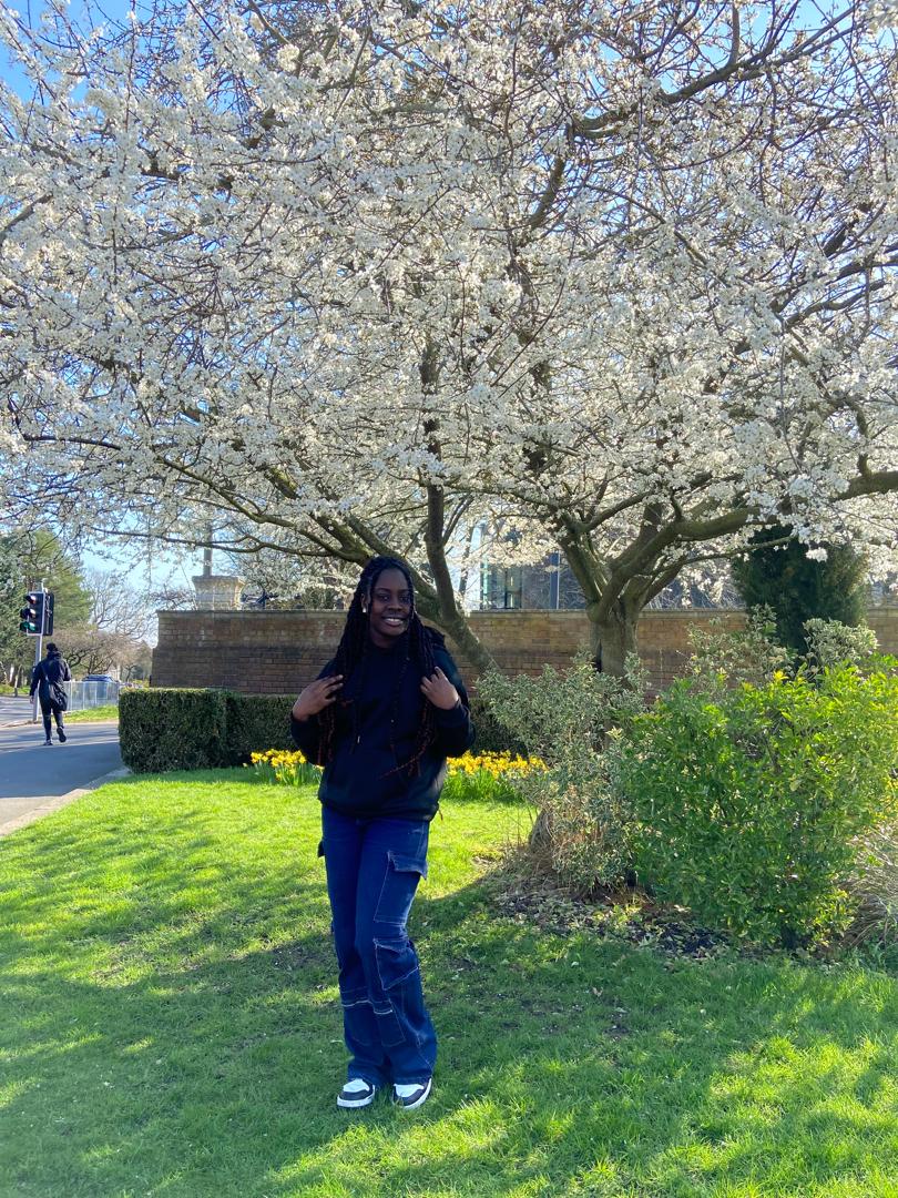 Student Ama is standing under a cherry blossom tree.