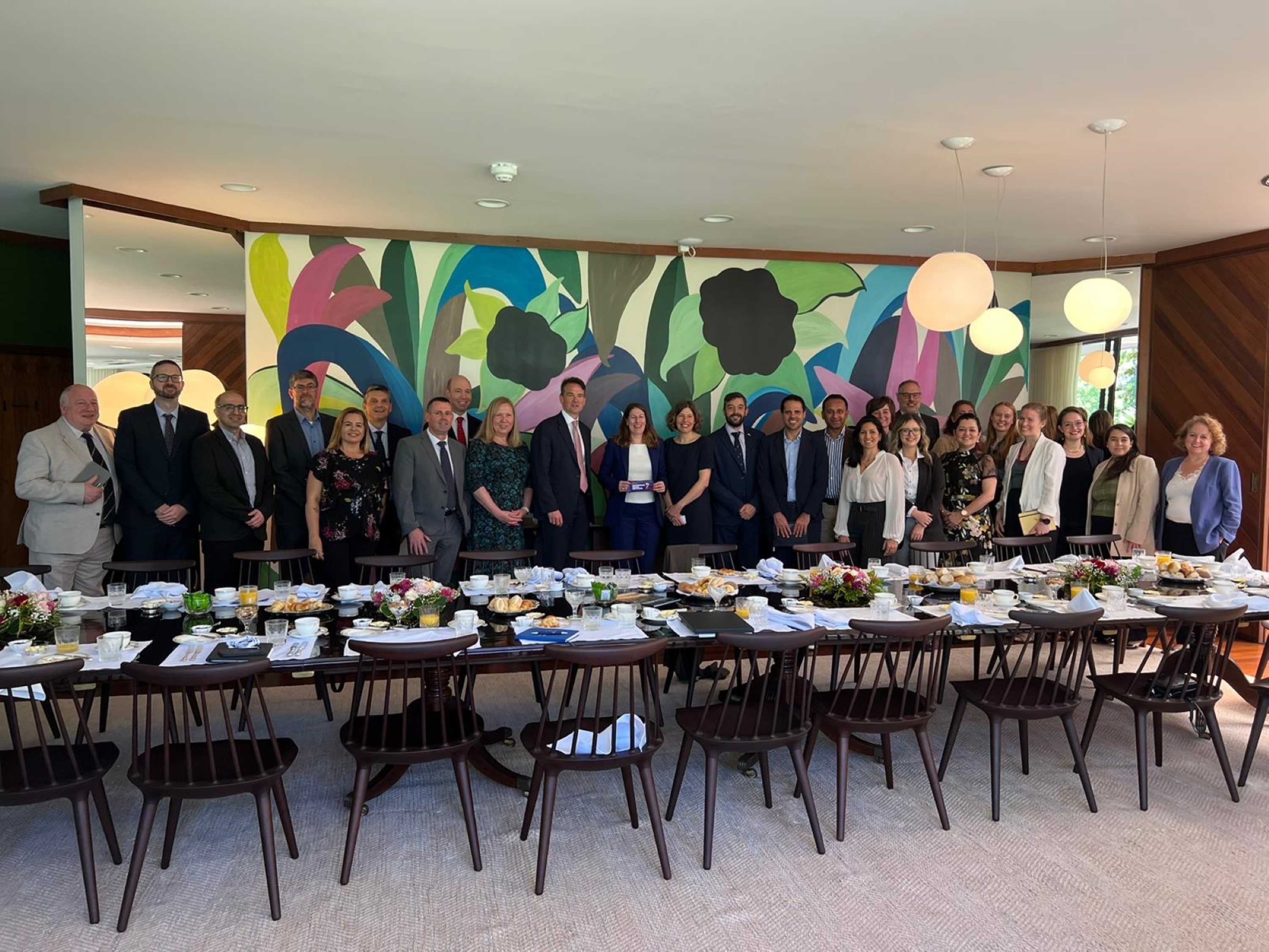Academics from Birmingham and Brazil standing in line behind a breakfast table