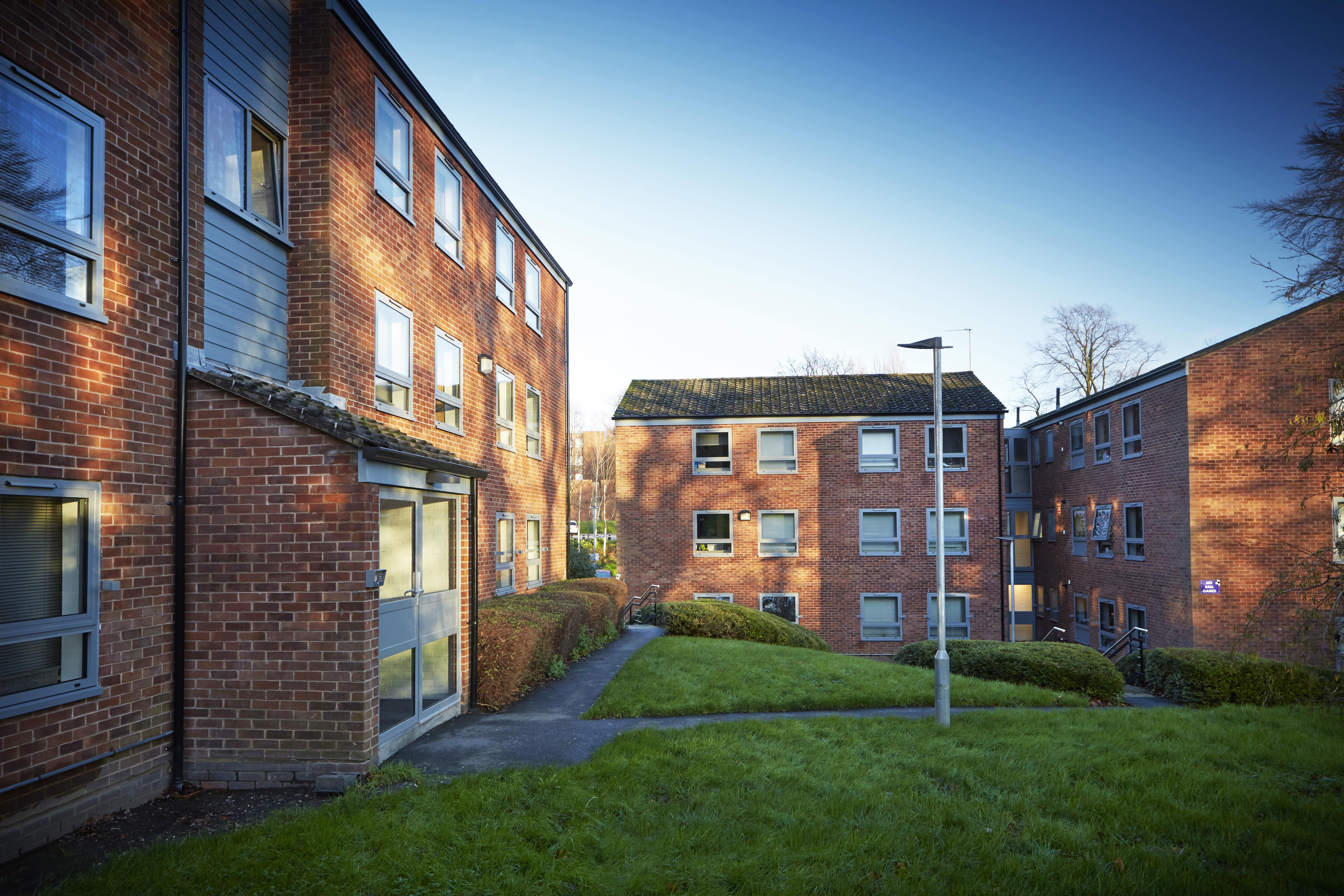 Three‑storey brick apartment buildings surrounded by green lawns.