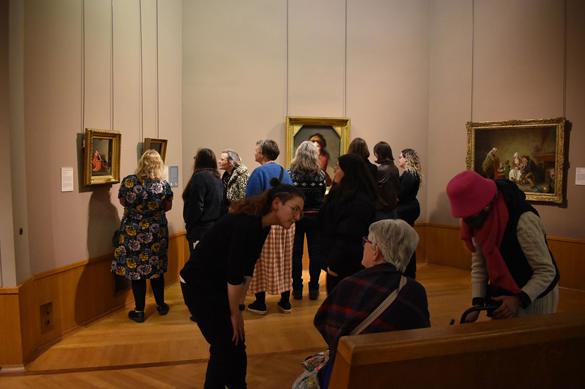 Visitors standing in an art gallery looking at paintings