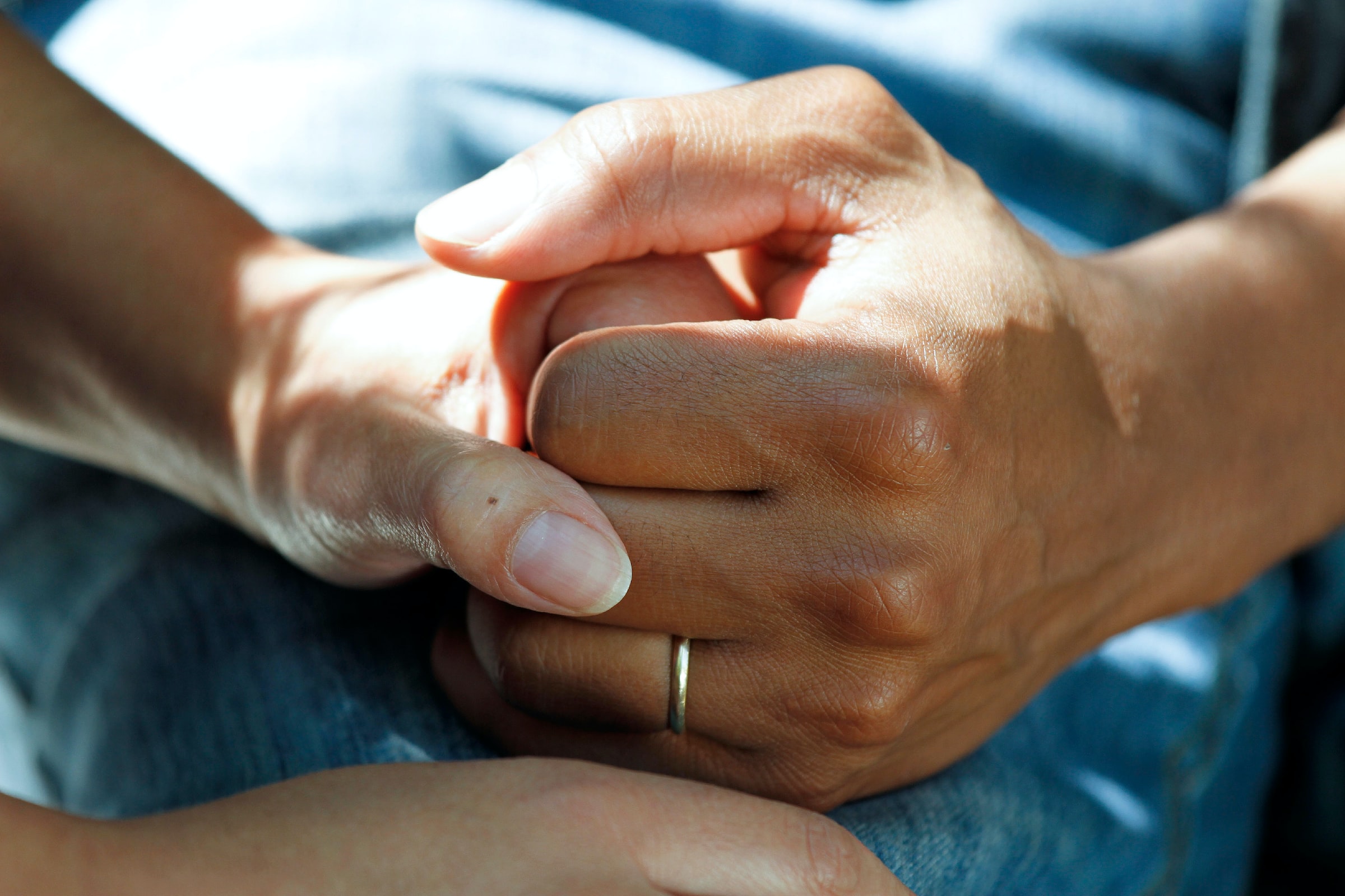 Picture of two hands holding either other in close up, giving comfort