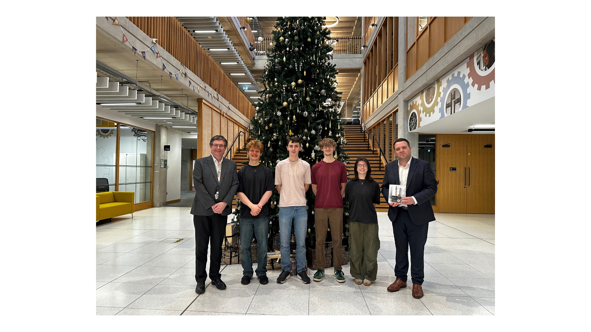 The four winners standing in front of a christmas tree with two Professors.