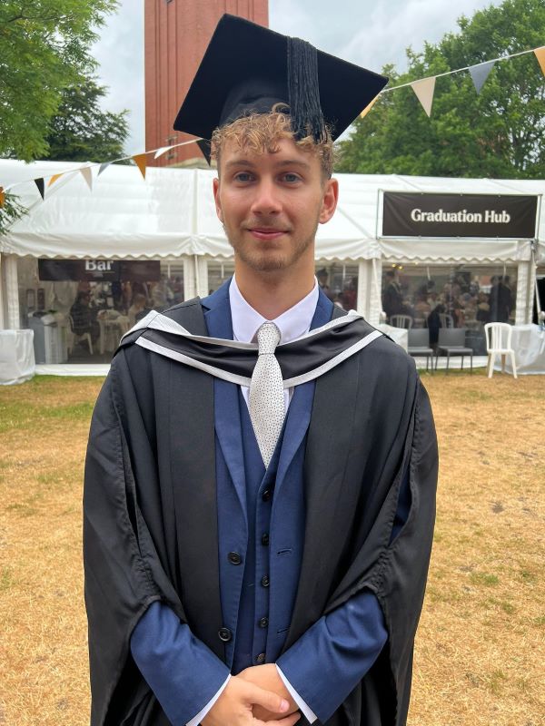 Ben poses in his graduation cap and gown, outside the Old Joe clock tower.