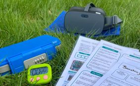 A virtual reality headset timer and locked box on some grass