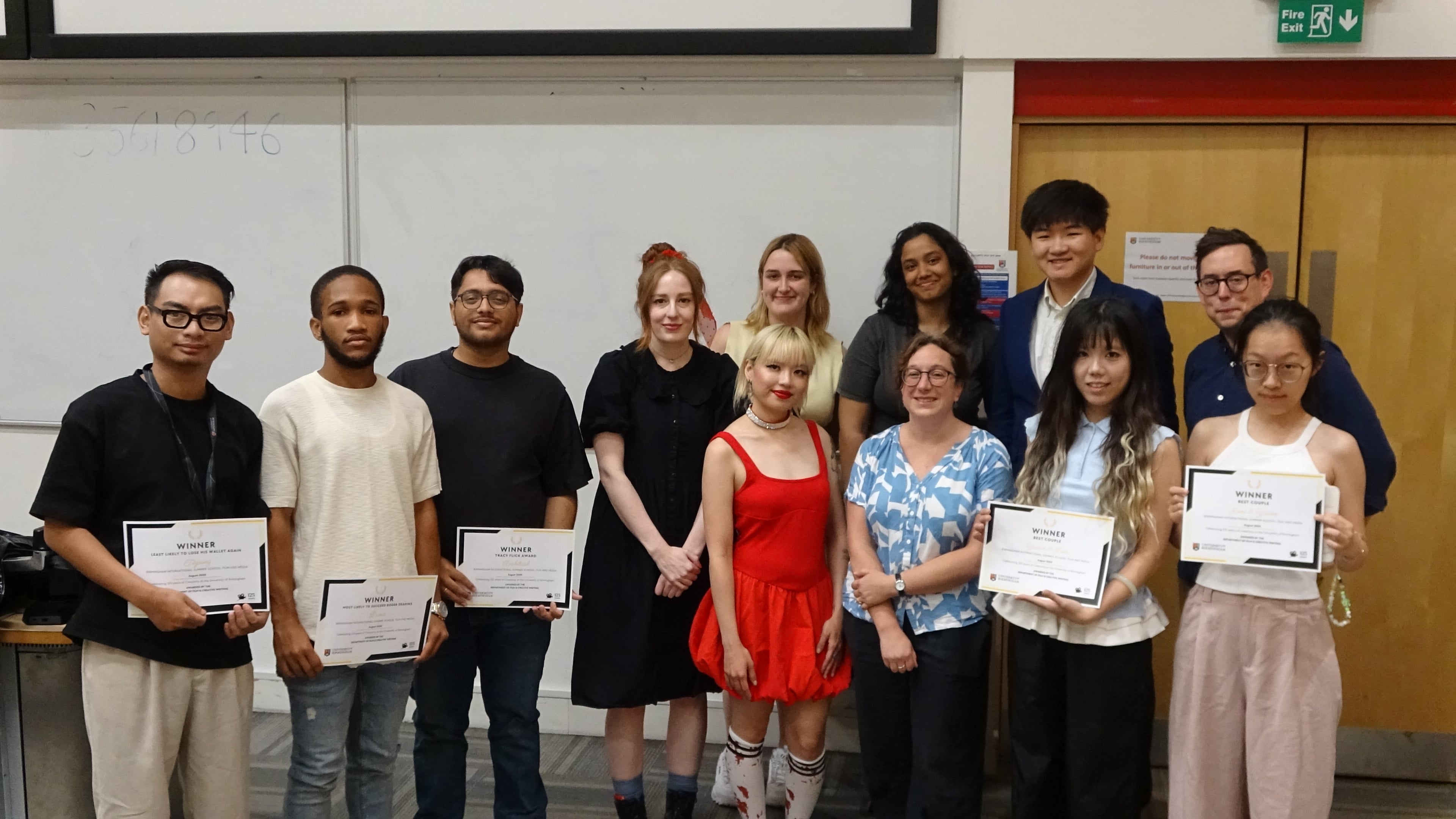 Summer school students posing with their lecturers holding completion certificates
