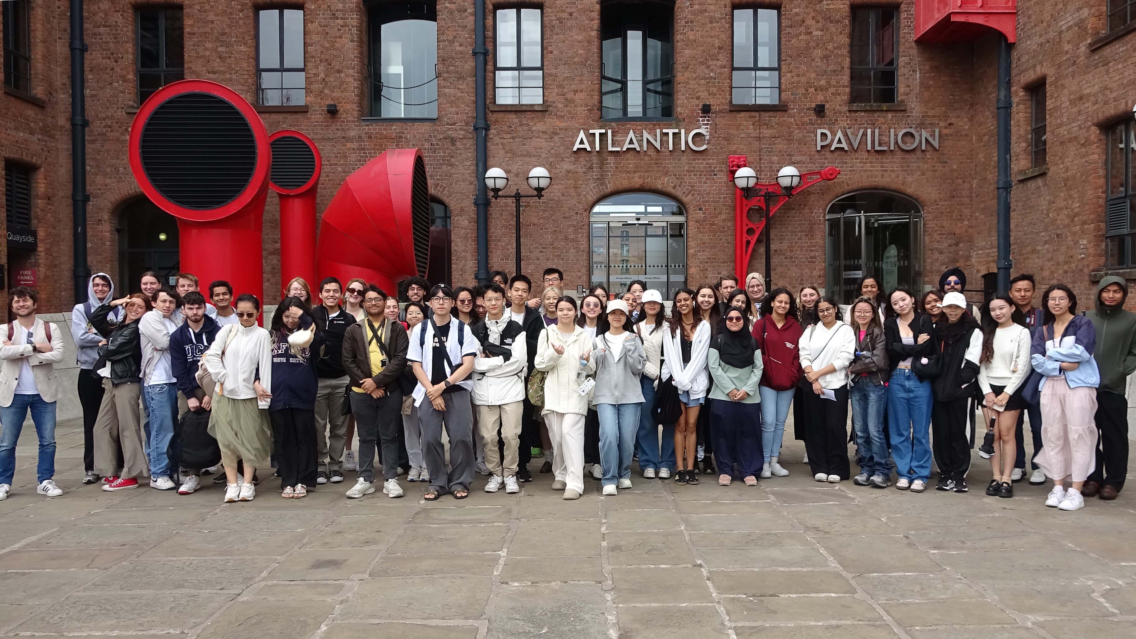 Summer school student group posing for picture in front of Atlantic pavilion in Liverpool