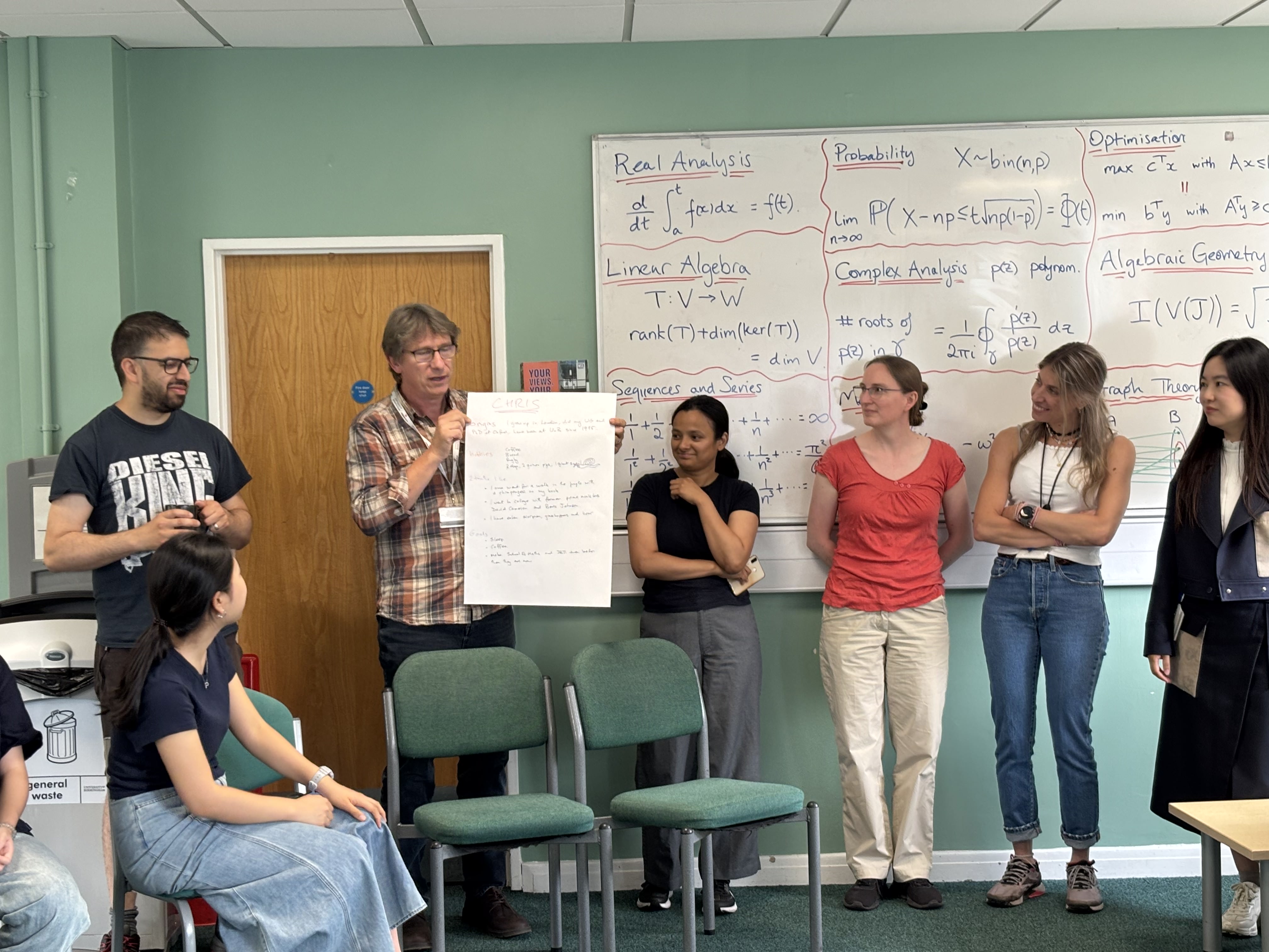 A lecturer holding a hand written white board for the Summer school students