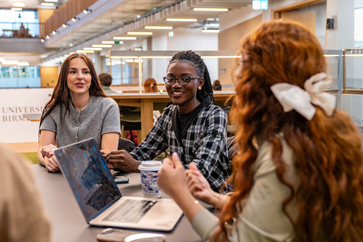 Three female students smiling and working together in a study area