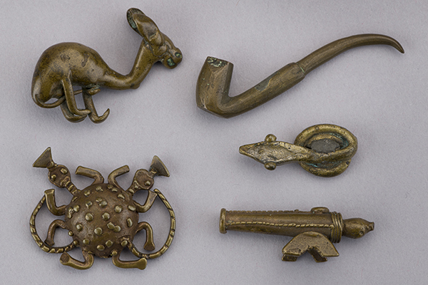 Five metal weights, each depicting a different figurative object including a cannon, three animals and a pipe.