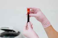 Close up of human hands holding a research vial containing blood for testing
