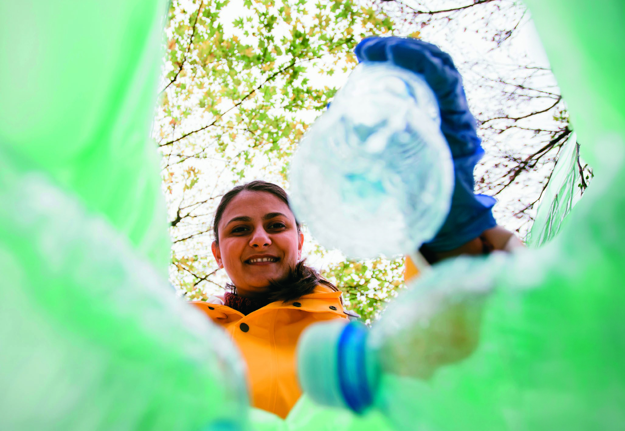 A woman looks down into a bag she is filling with used plastic bottles.