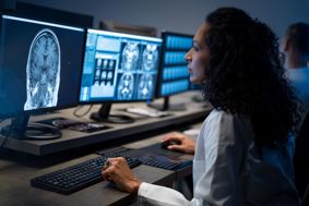 A doctor looking at a brain scan image on a computer screen
