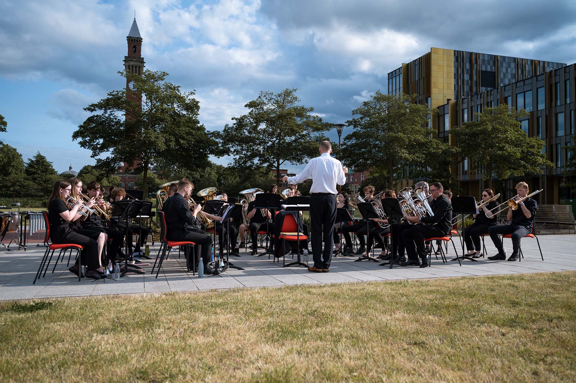 University Brass Band performing on the Birmingham campus in front of the clock tower and the library