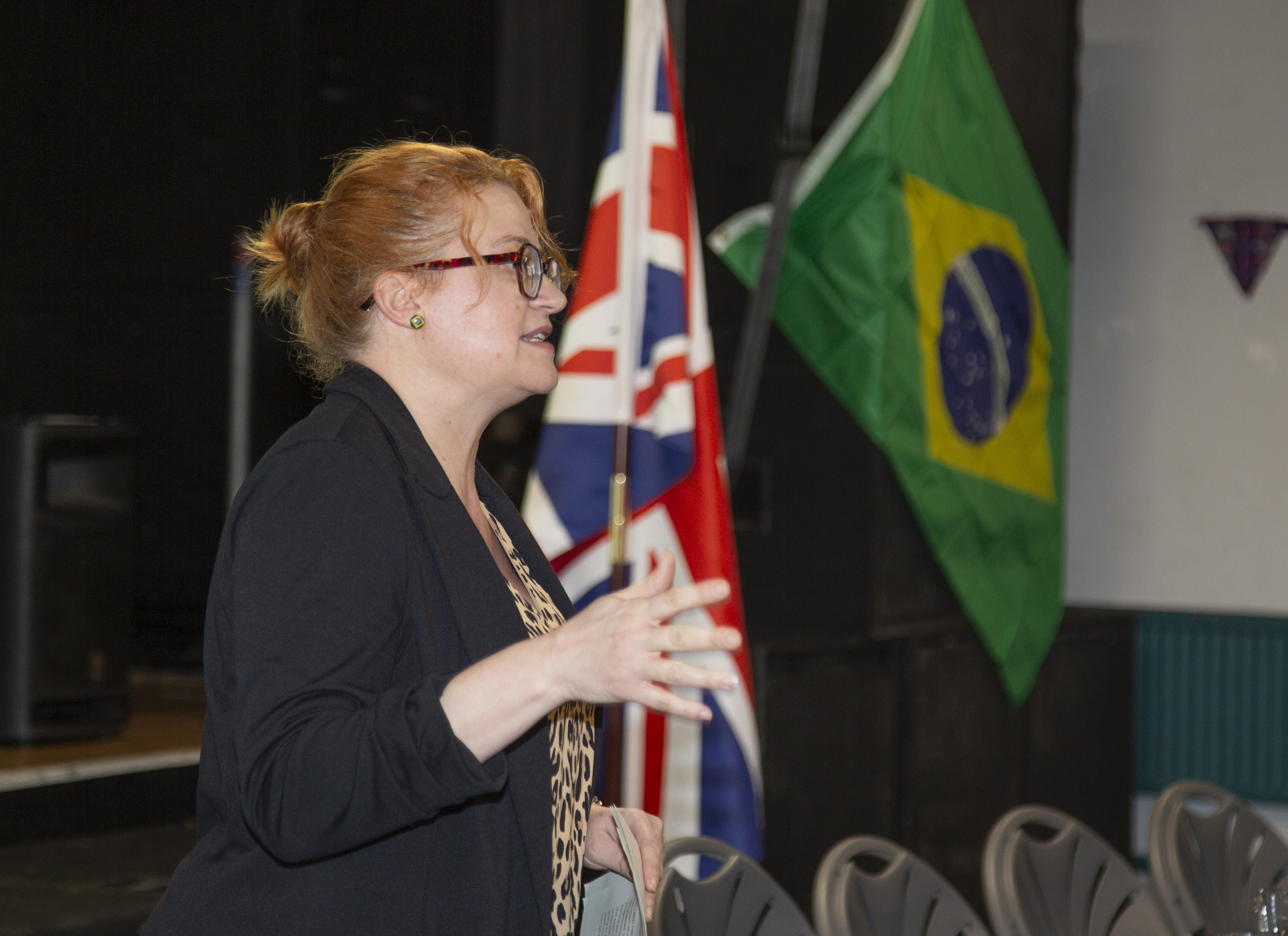 Brazil Institute Co-Director Courtney Campbell speaking to the audicence,with the Brazil and UK flags at the back