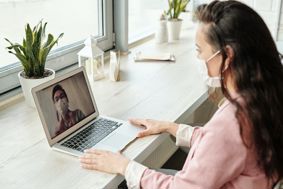 A patient speaking to a medical professional via video call on a laptop.