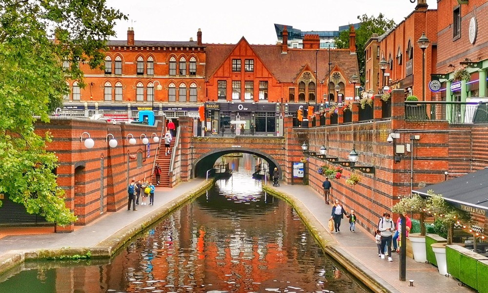 A view looking direclty down a stretch of urban canal with people walking each side