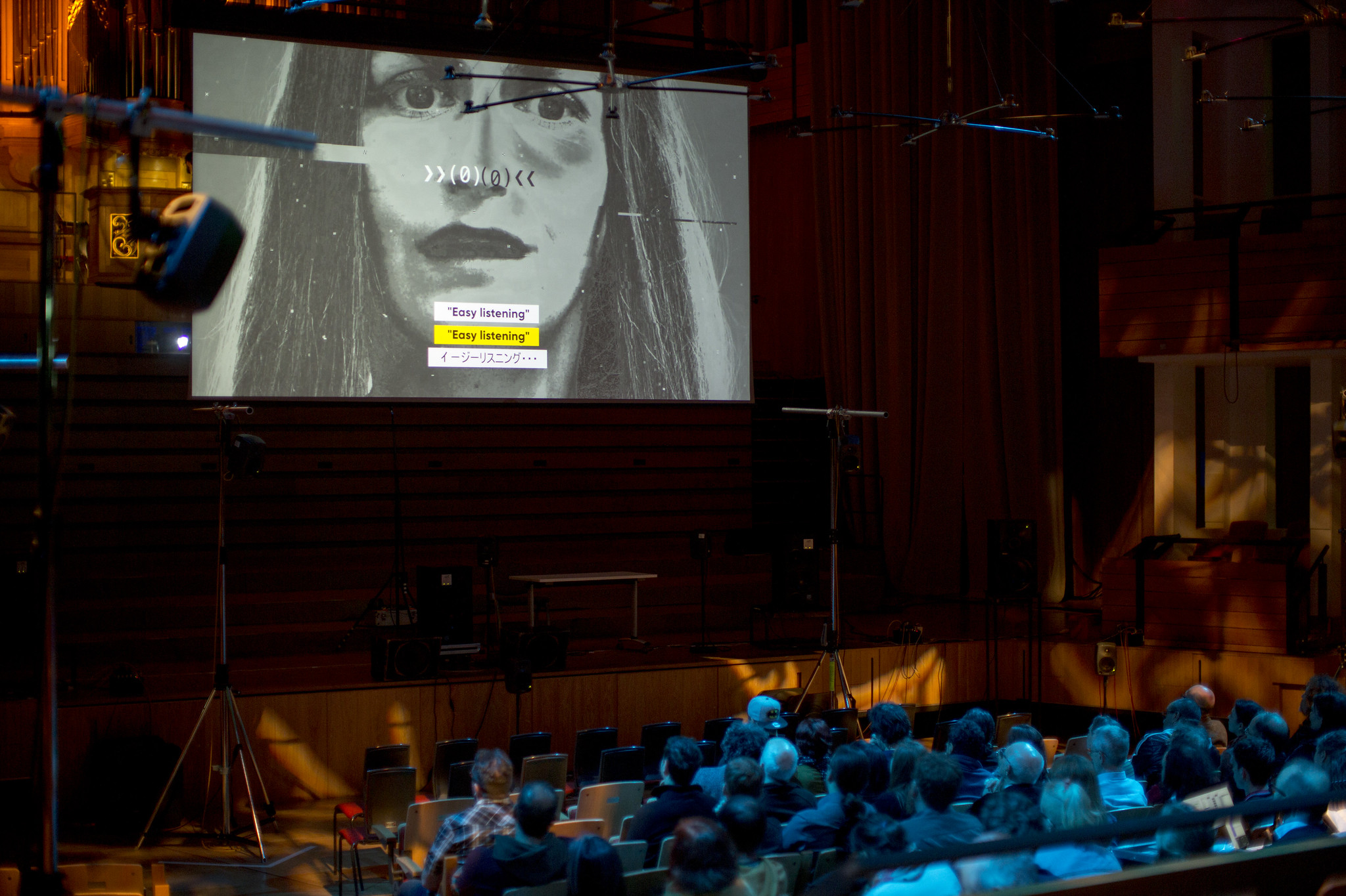 Audience in a large auditorium with a projection and speakers