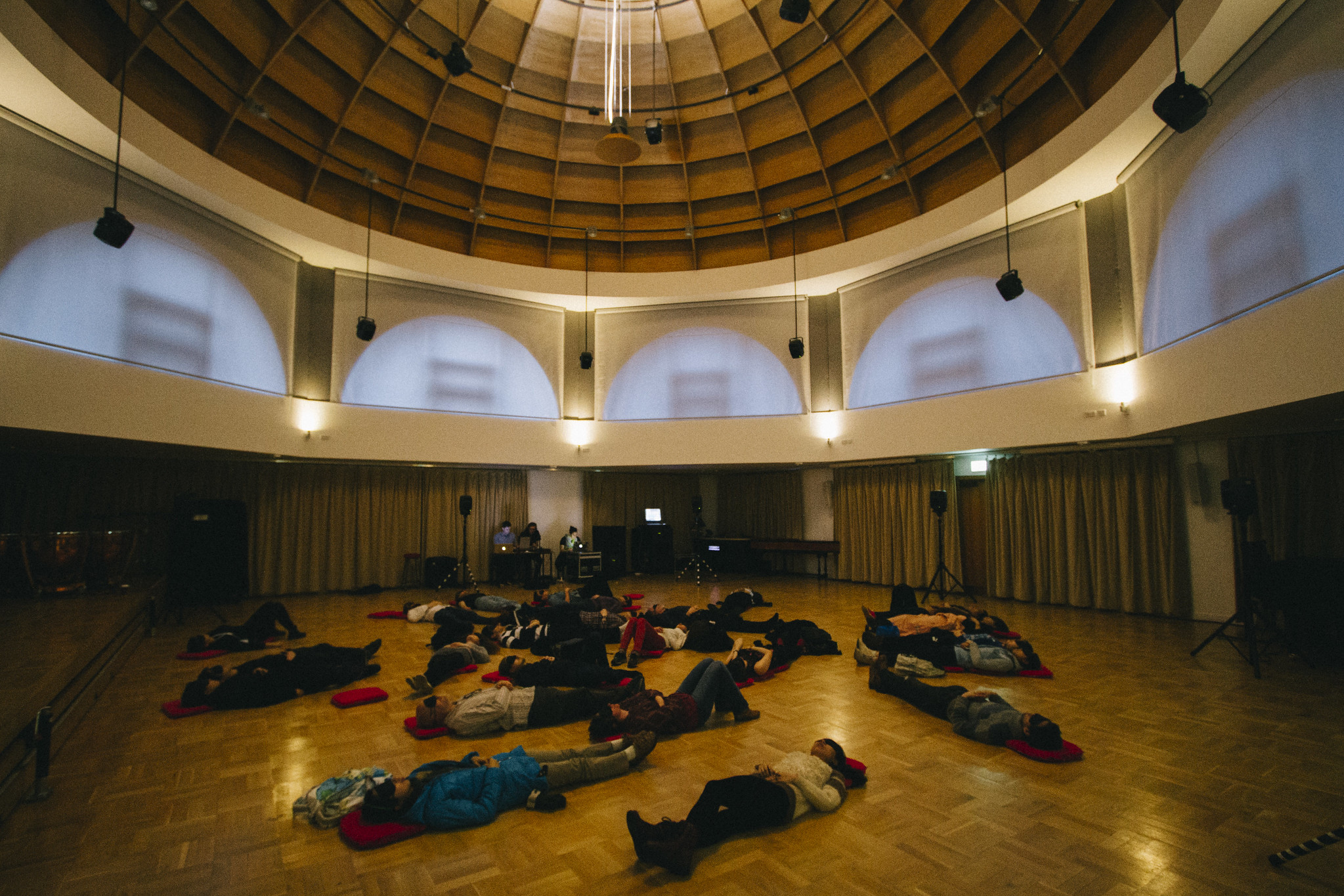 The blindfolded audience lying on the floor underneath a domed ceiling