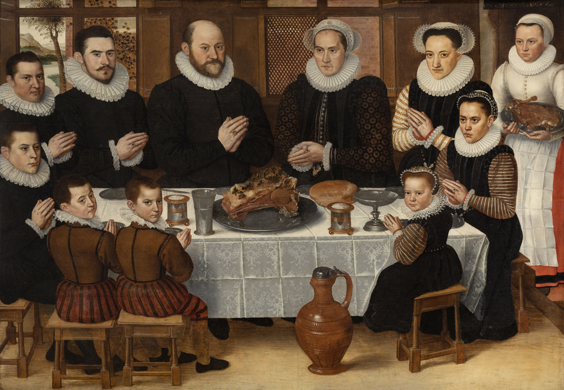 This image portrays a formal family meal in 16th-century Flanders, specifically captured in a painting titled A Family Saying Grace before a Meal by Antoon Claeissens, created around 1585