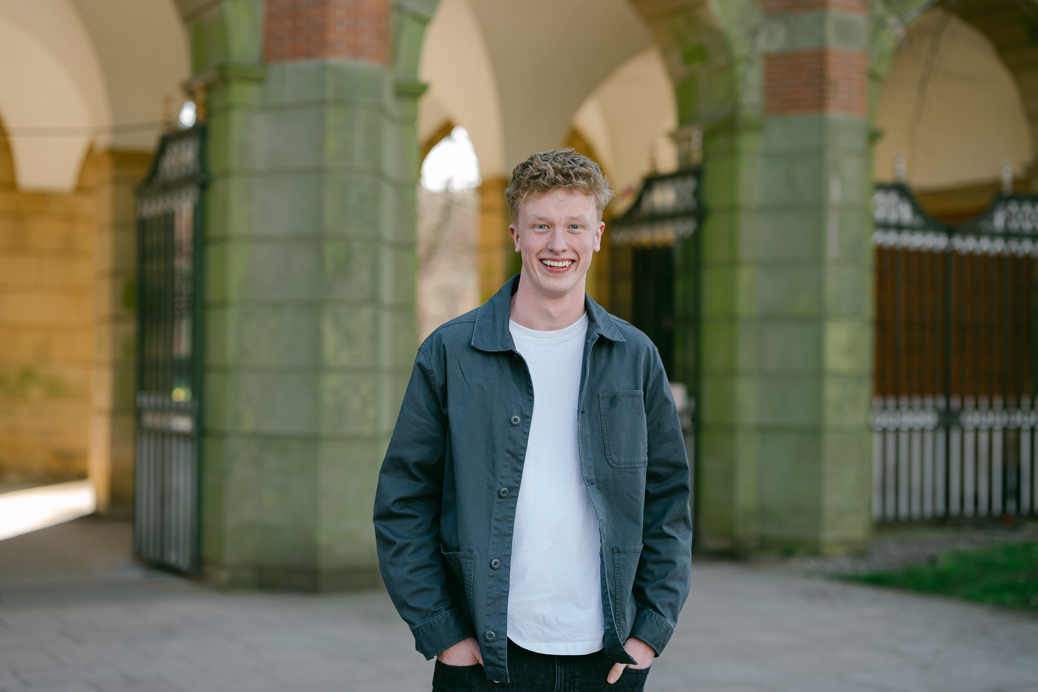 Student Jack stands in front of the gates to a building smiling