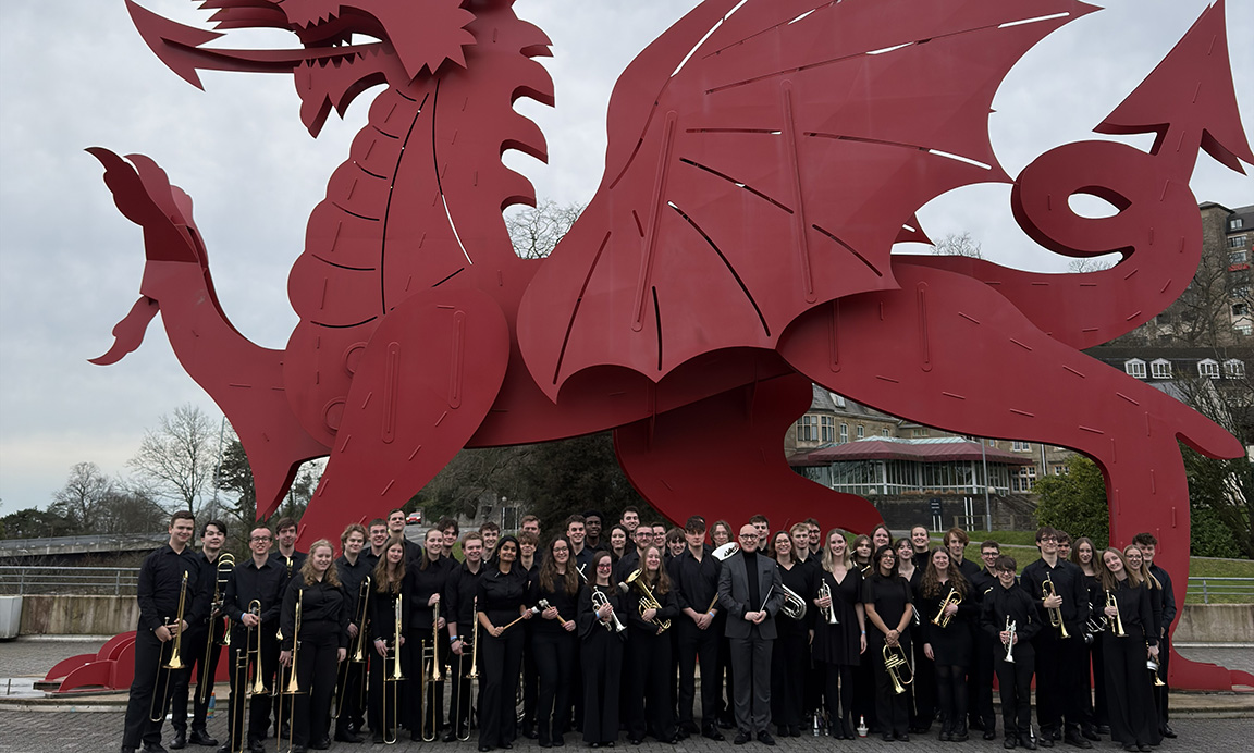 Students standing in front of statue of dragon