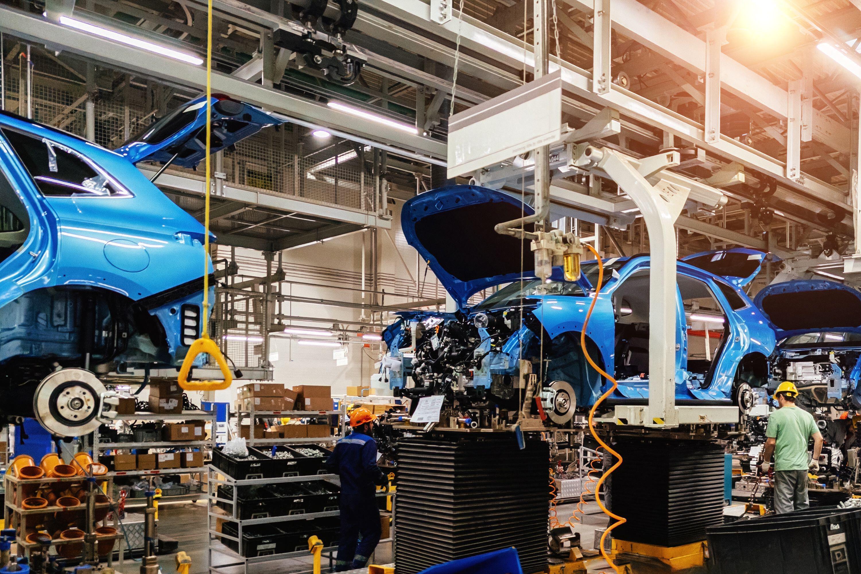 Multiple cars being put together on an assembly line in a factory