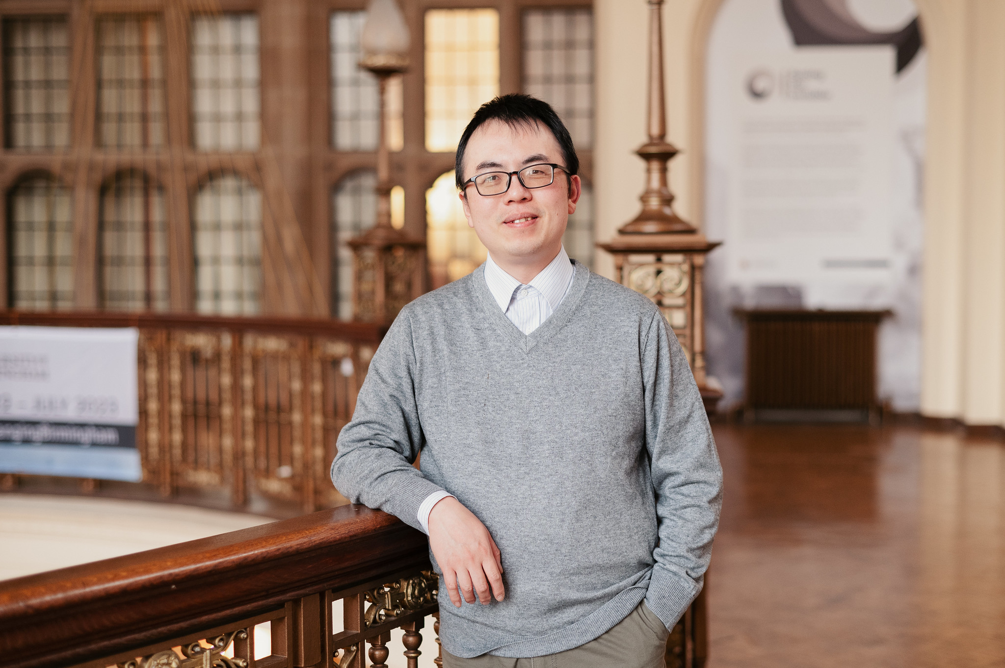 Dr Chen Zhu standing in the atrium of the University of Birmingham Great Hall
