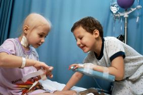 Two children in a hospital playing together while receiving cancer treatment