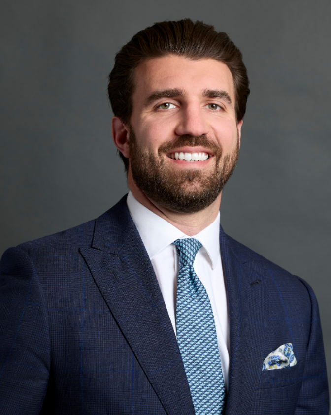 A male student in a suit smiling and looking at the camera