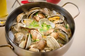 A large cooking pot filled with clams and stock